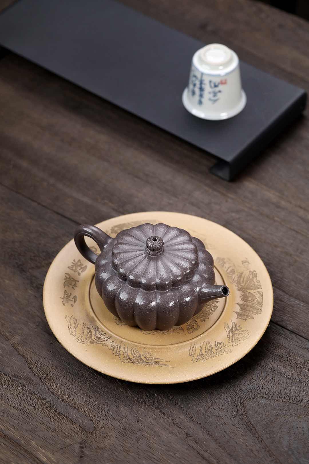 Handmade Yixing purple sand teapot on an artistic plate, showcasing traditional craftsmanship.