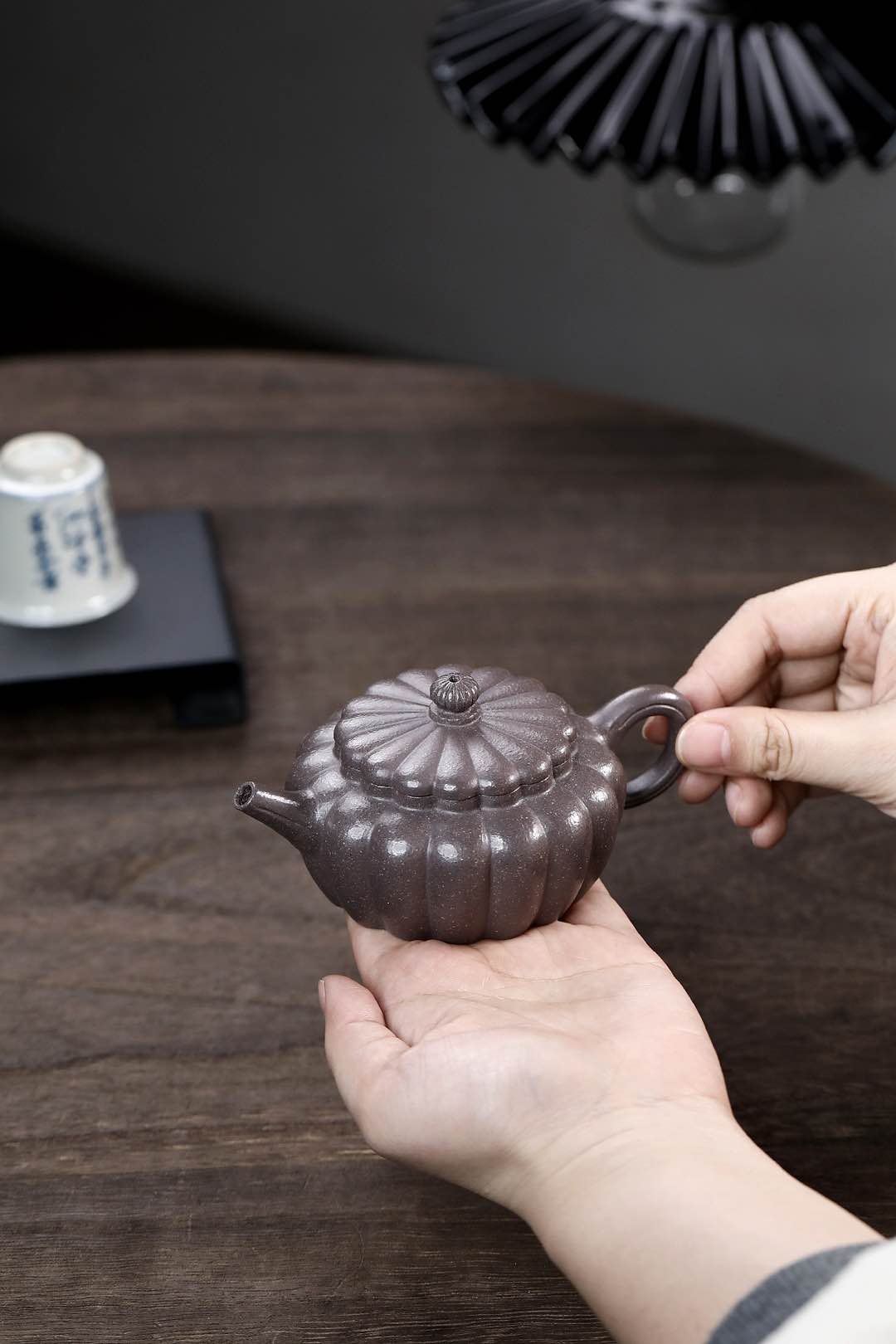 Handmade Yixing purple sand teapot in a person's hand, showcasing traditional craft design.