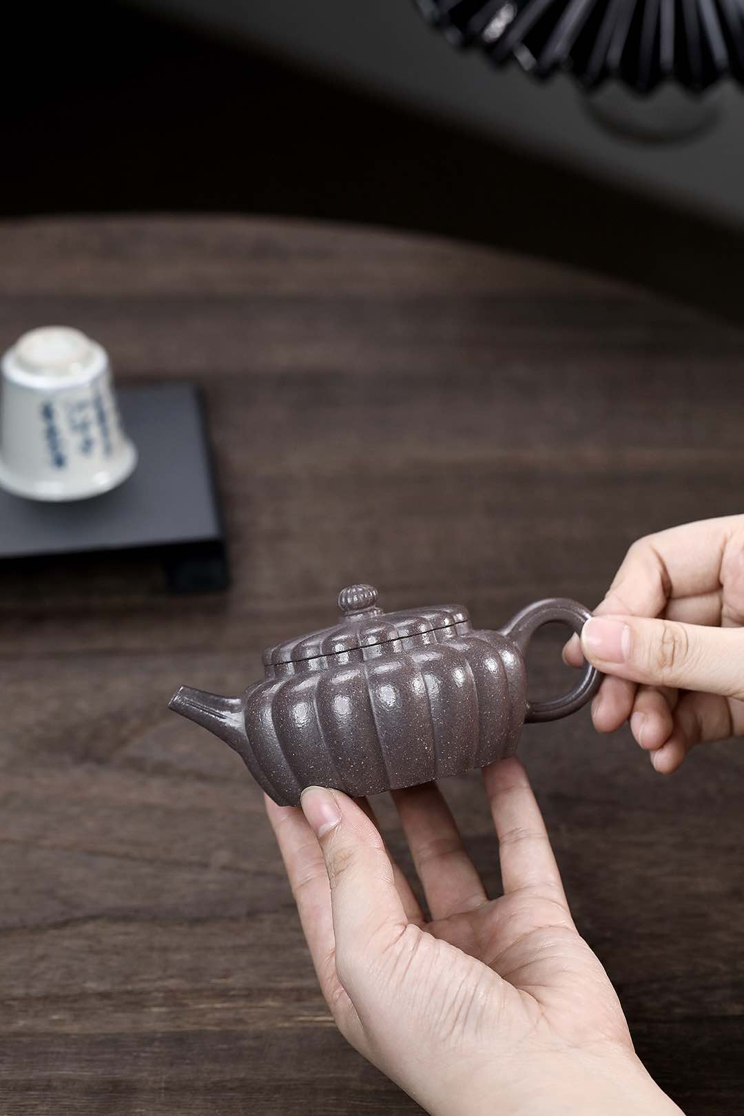 Handmade Yixing purple sand teapot with a unique design held in hand, showcasing artisan craftsmanship.