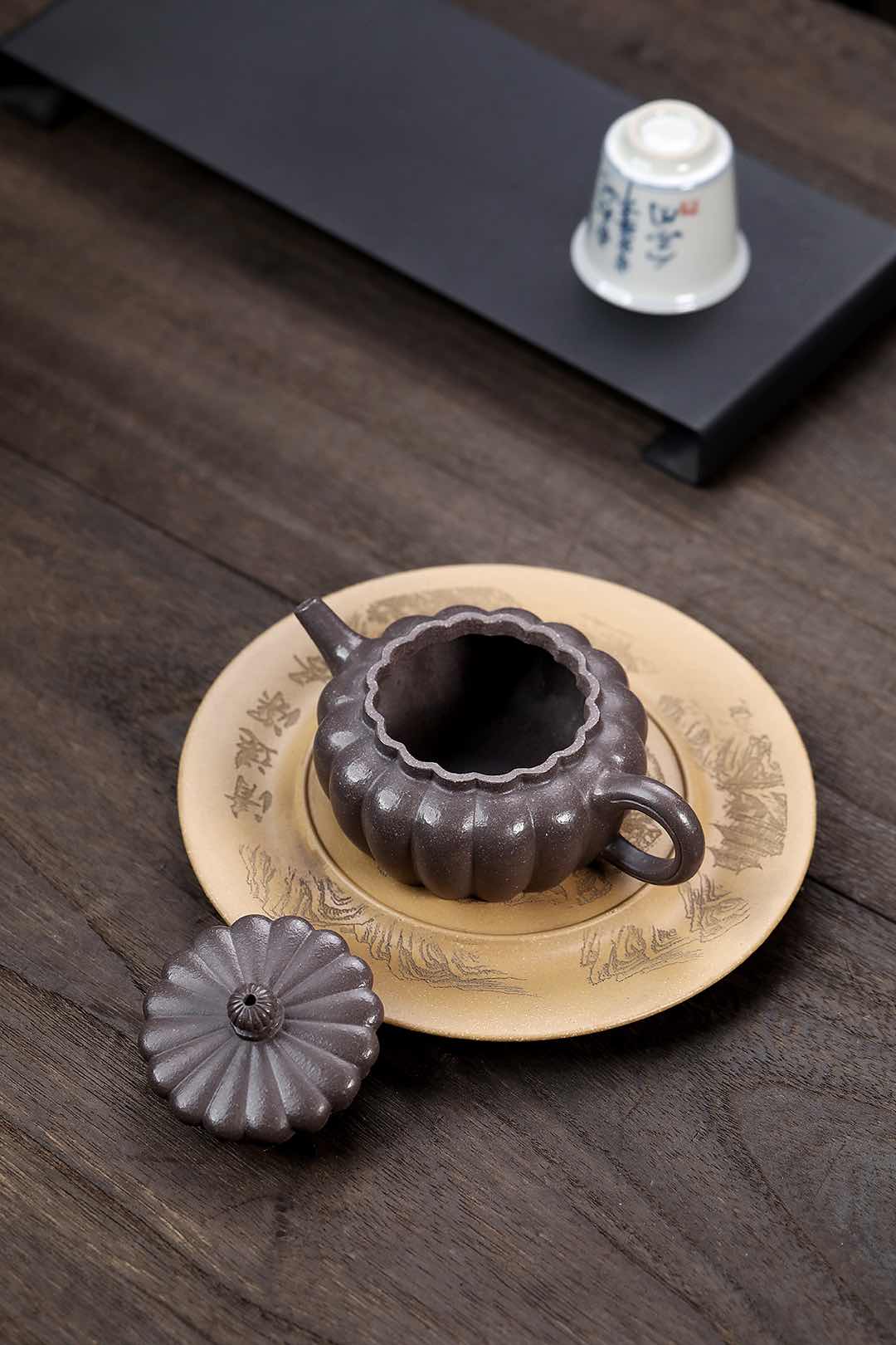 Handmade Yixing purple sand teapot with a round tray, showcasing intricate craftsmanship and traditional design.
