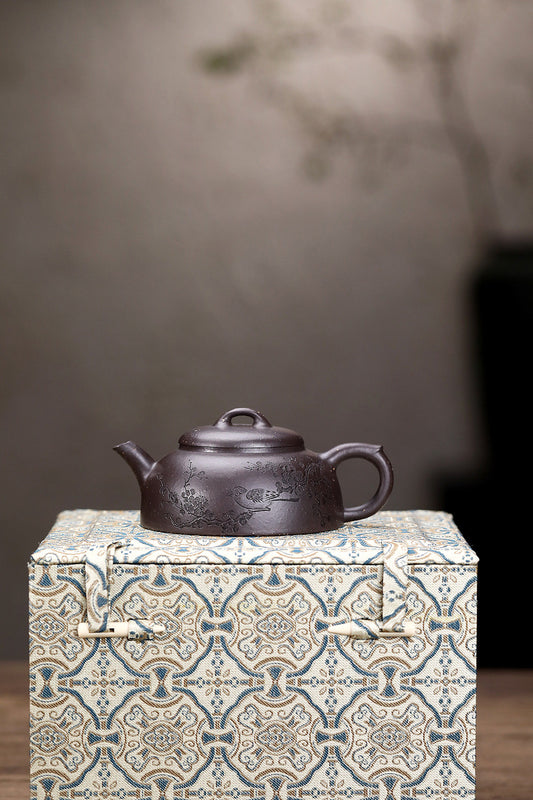 Handmade Yixing purple sand teapot displayed on a decorative gift box, showcasing unique craftsmanship and design.