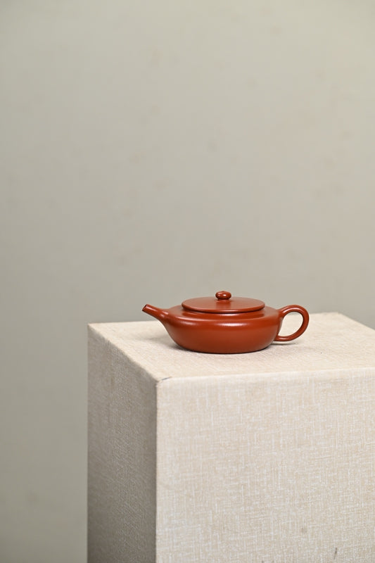Handmade Yixing purple sand teapot on display, featuring a sleek design and rich reddish-brown color.