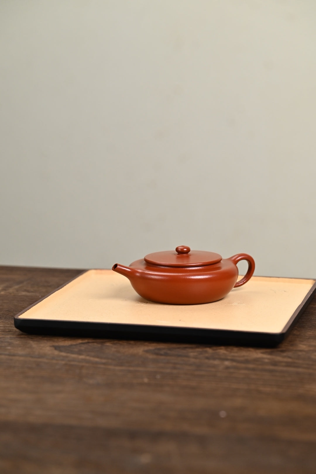 Handmade Yixing purple sand teapot in rich red clay on a wooden surface, showcasing fine craftsmanship.