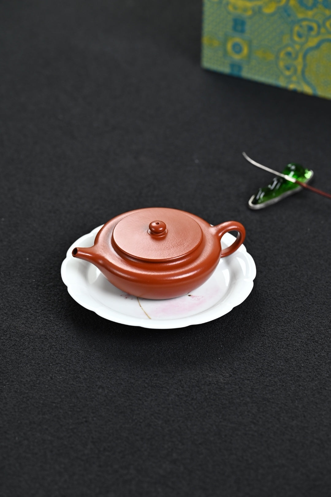 Handmade Yixing purple sand teapot on a white plate, crafted by master Wang, showcasing exquisite design.