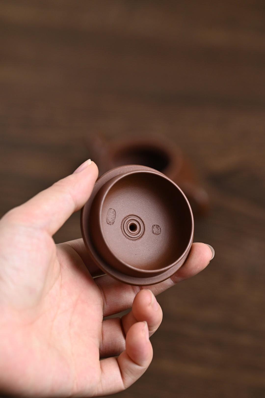 Handmade Yixing purple sand teapot base showing 7 water holes, showcasing craftsmanship by artist Chen Huajun.