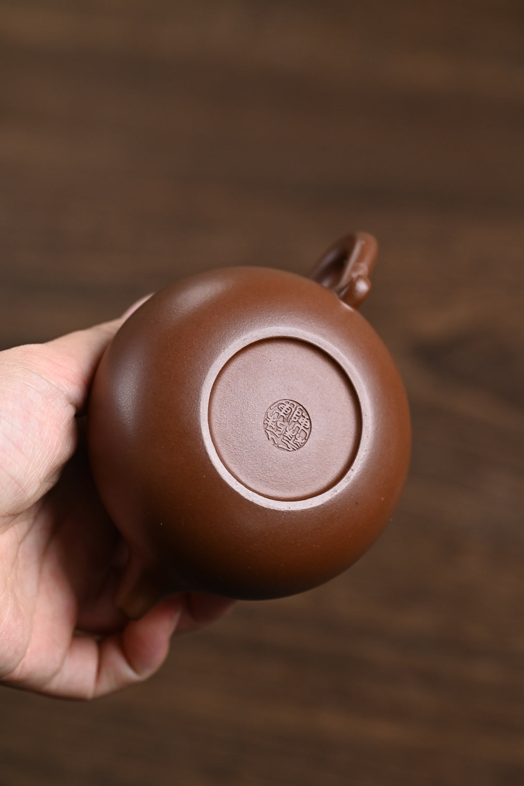Handmade Yixing purple sand teapot base showing craftsmanship and branding, perfect for tea enthusiasts.
