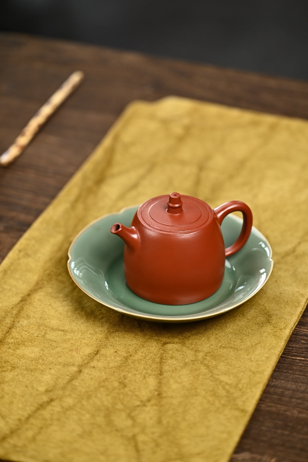 Handmade Yixing purple sand teapot on a green plate, showcasing traditional craftsmanship.