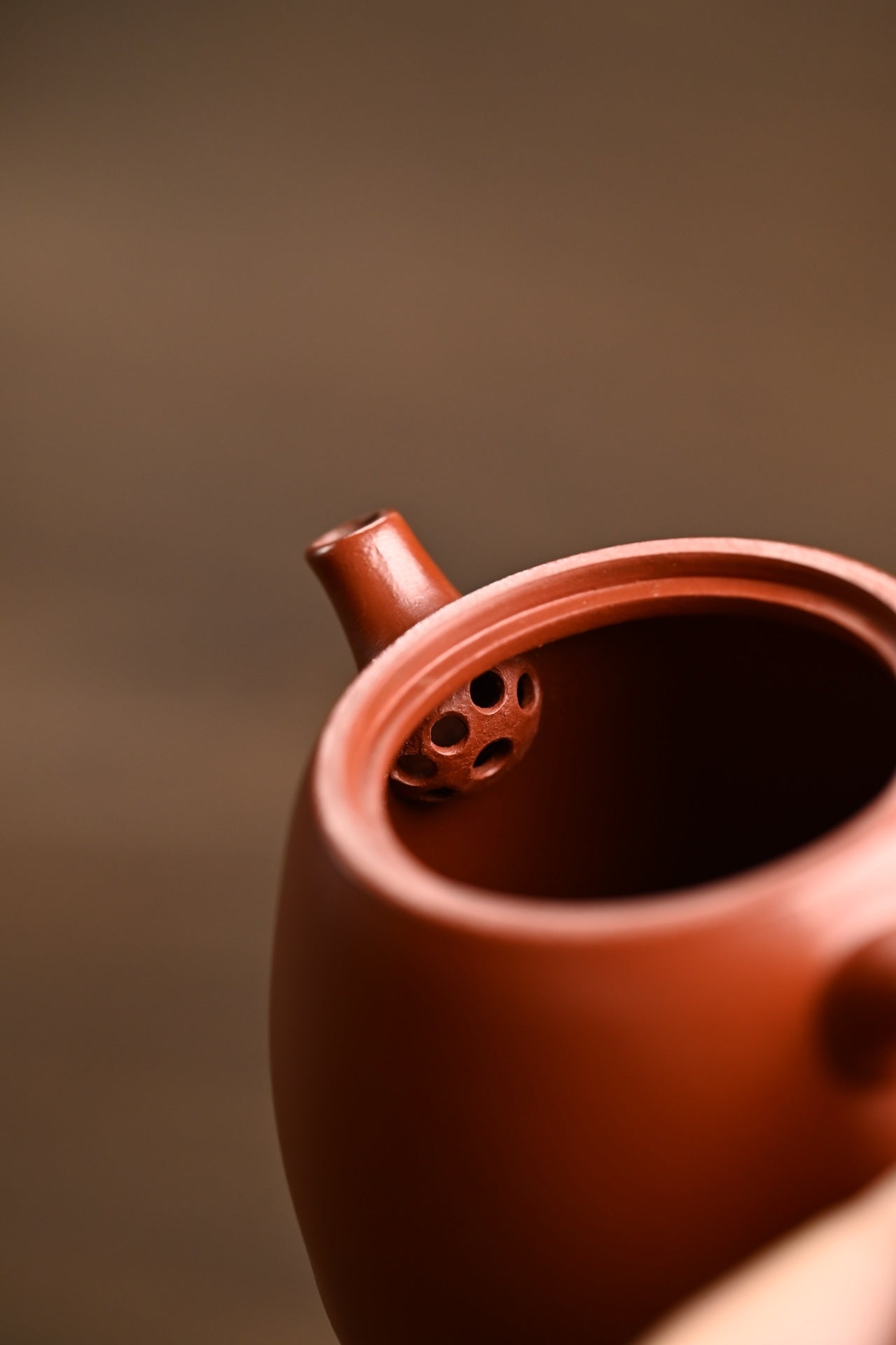 Close-up of a handmade Yixing purple sand teapot showing its inner spout with 7 holes for easy pouring.