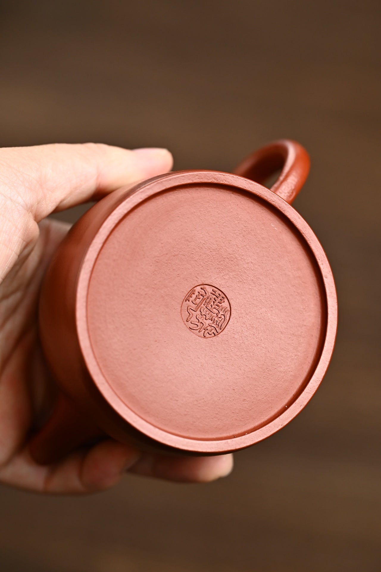 Close-up of the bottom of a handmade Yixing purple sand teapot by Sun Jianfang, showcasing the artisan's seal.