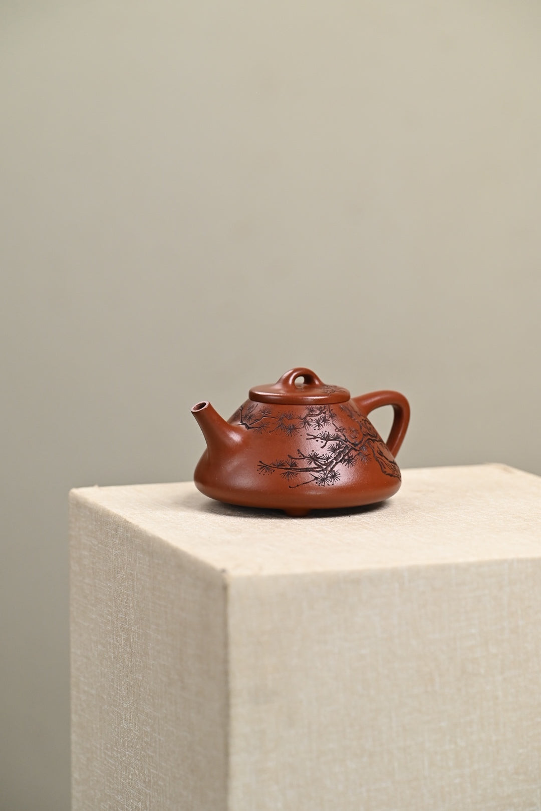 Handmade Yixing purple sand teapot featuring intricate floral designs, displayed elegantly on a pedestal.