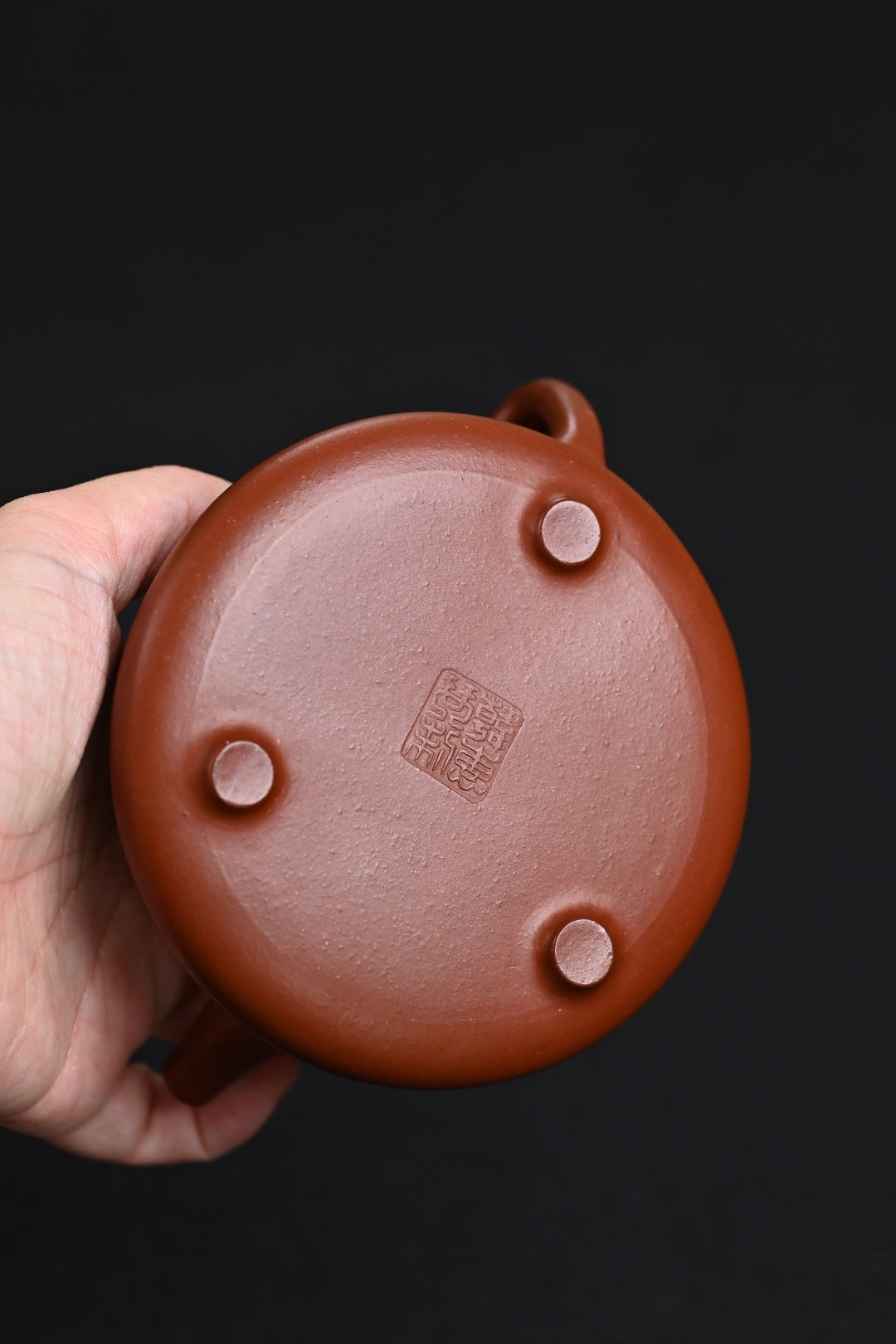 Bottom view of a handmade Yixing purple sand teapot showcasing its artisan craftsmanship and original clay material.