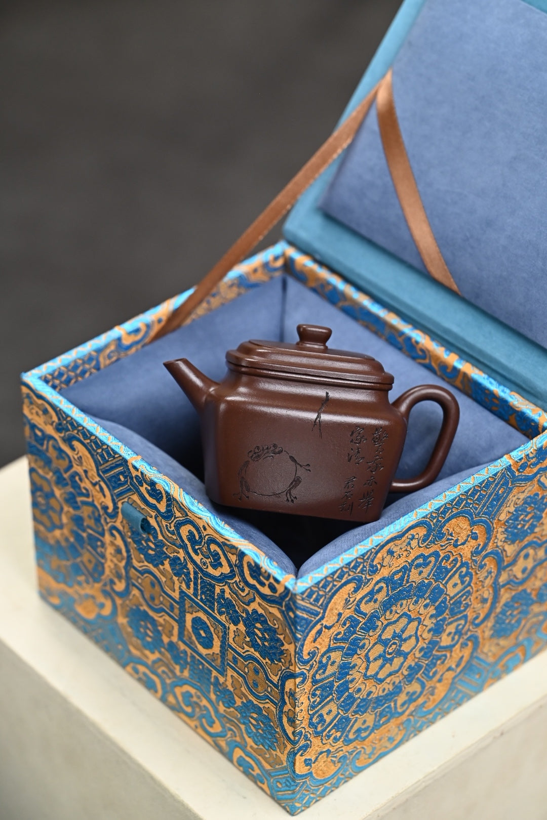 Handmade Yixing purple sand teapot displayed in an ornate gift box, showcasing fine craftsmanship.