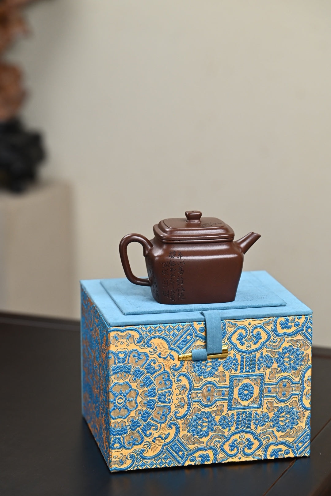 Handmade Yixing purple sand teapot displayed on a blue and gold ornate box, showcasing exquisite craftsmanship.