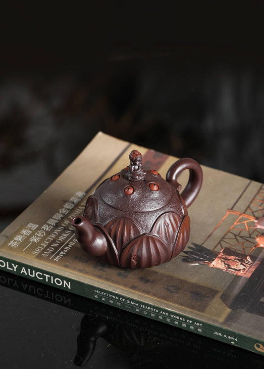Handmade Yixing purple sand teapot with intricate design, displayed on an art catalog.