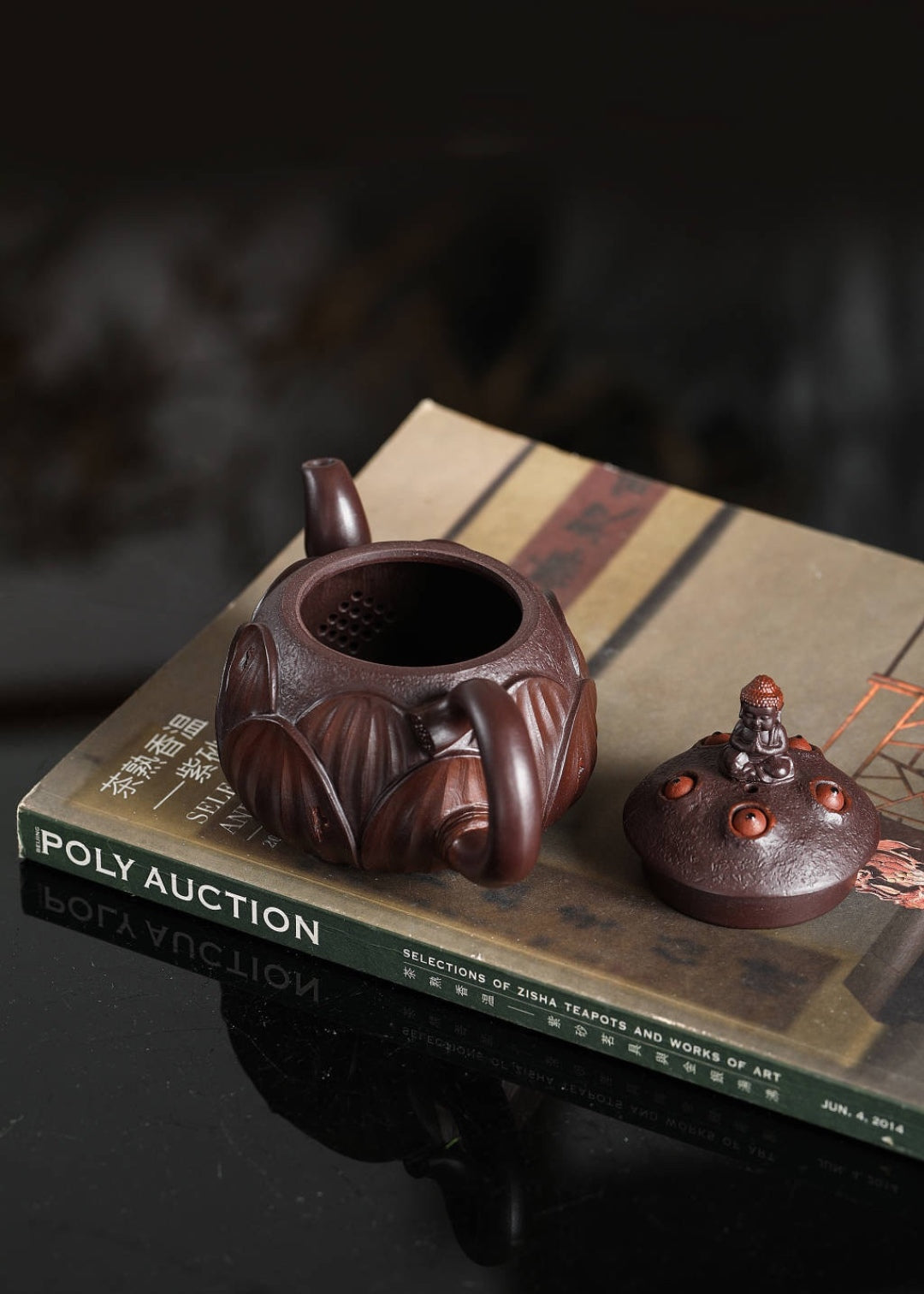 Handmade Yixing purple sand teapot displayed on an art book, showcasing intricate design and craftsmanship.