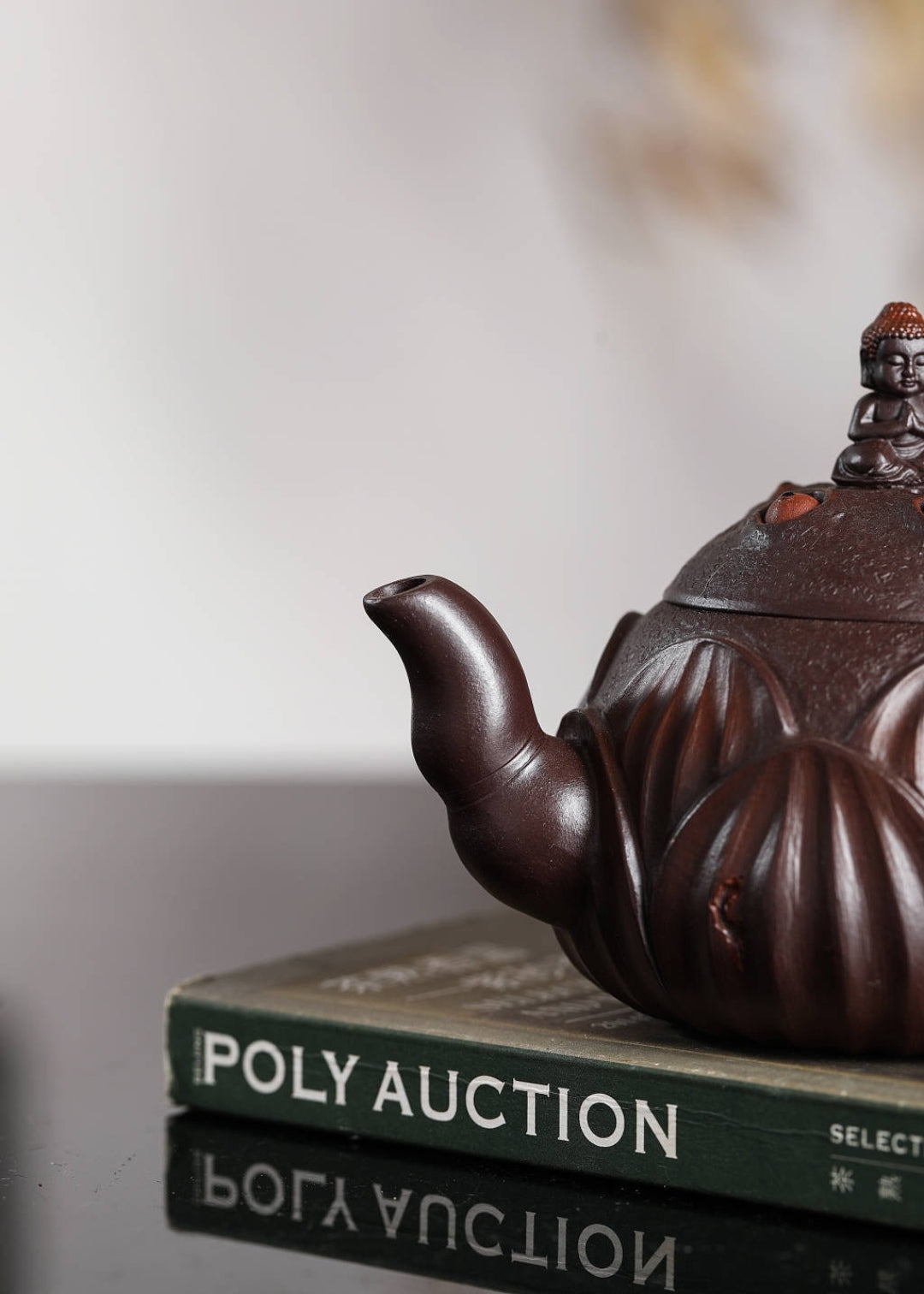 Handmade Yixing purple sand teapot displayed on a book, showcasing its intricate design and craftsmanship.