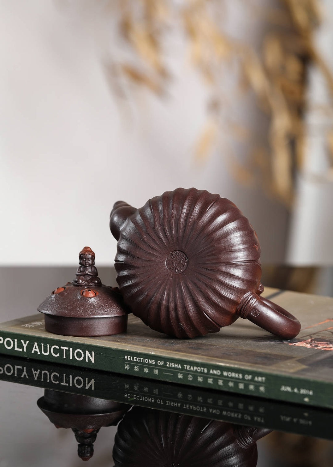Handmade Yixing purple sand teapot with intricate design displayed on a book, showcasing traditional craftsmanship.