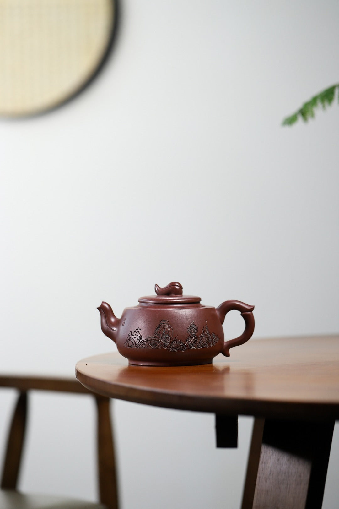 Handmade Yixing purple sand teapot with intricate design, displayed on a wooden table.