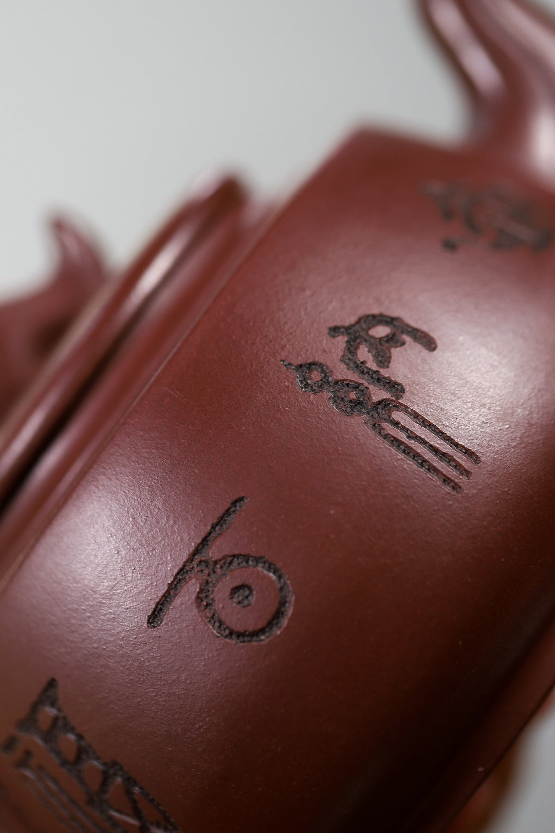 Close-up of handmade Yixing purple sand teapot featuring intricate engravings and craftsmanship details.