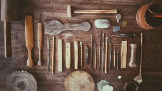 Collection of various crafting tools on a wooden table, showcasing handmade craftsmanship.
