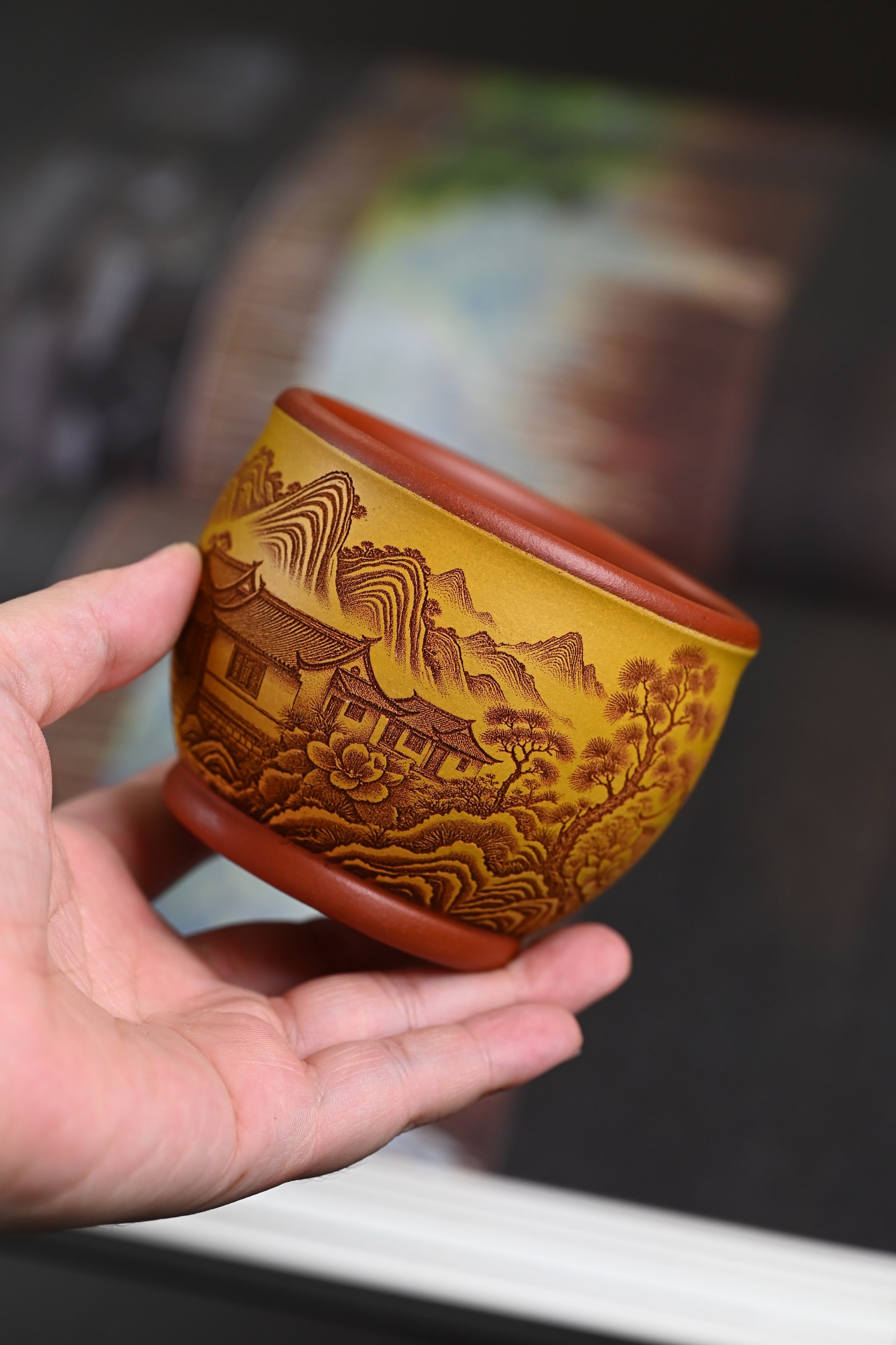Handmade Yixing Zisha cups crafted from original purple sand by skilled artisans, featuring floral designs and warm colors.