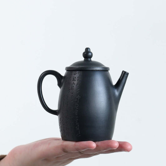 Handmade Yixing purple sand teapot held in hand, showcasing elegant craftsmanship and traditional design.