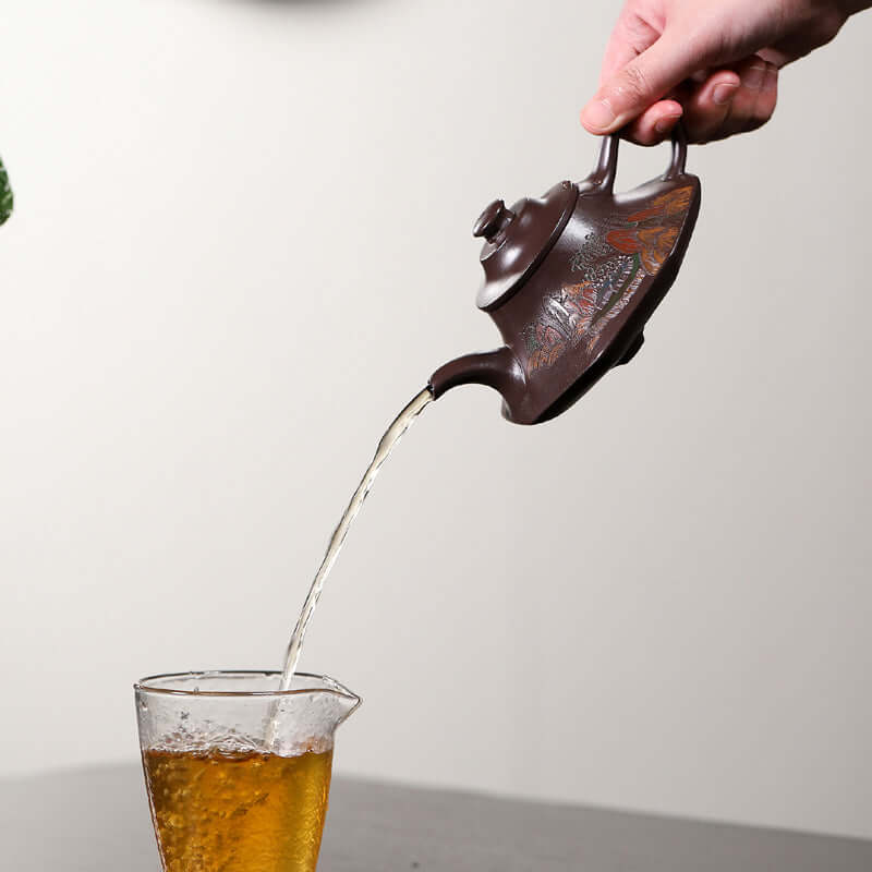 Handmade Yixing purple sand teapot elegantly pouring tea into a glass, showcasing traditional craftsmanship.