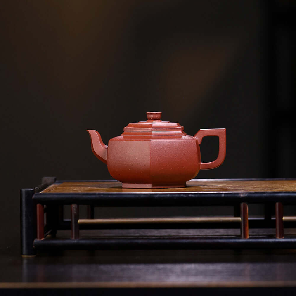 Handmade Yixing purple sand teapot displayed on a wooden stand, showcasing exquisite craftsmanship and design.