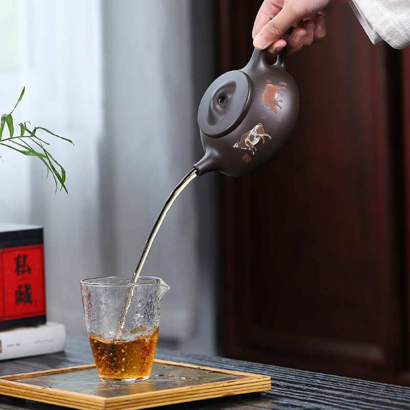 Handmade Yixing purple sand teapot pouring tea into a glass cup, showcasing traditional kung fu tea ceremony.