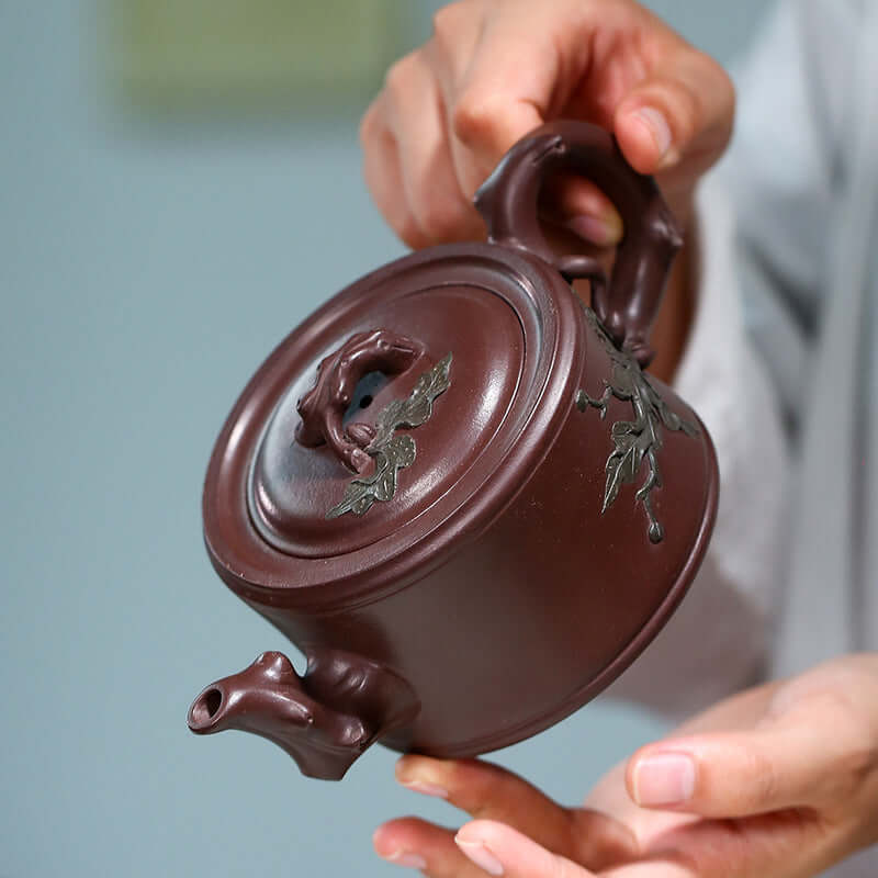 Handmade Yixing purple sand teapot with intricate leaf design, showcasing expert craftsmanship and unique artistry.
