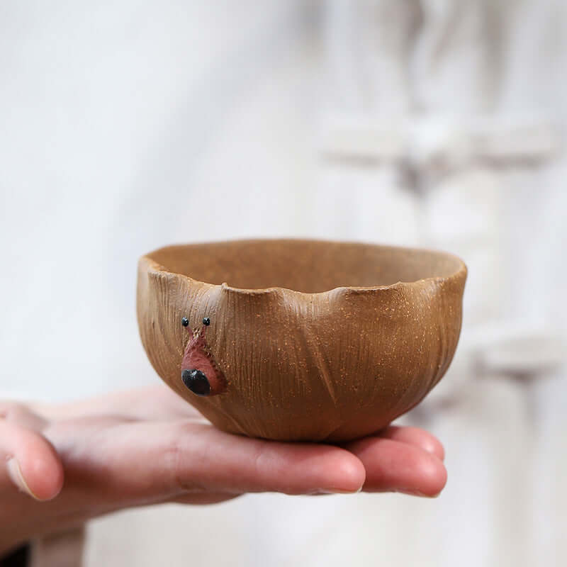 Handmade Yixing purple sand tea cup featuring unique design, held in hand, highlighting artisan craftsmanship.