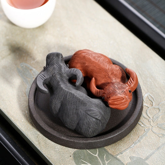 Handmade Yixing purple sand tea pets in black and red, nestled on a decorative tray, perfect for tea play and lucking ornaments.