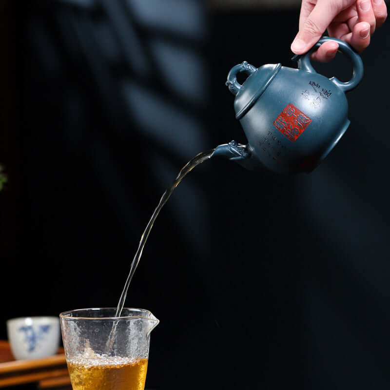 Handmade Yixing purple sand teapot pouring tea into a glass cup, highlighting its elegant design and craftsmanship.