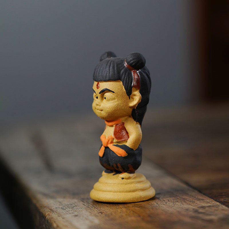 Handmade Yixing purple sand Nezha anime character tea pet ornament on a wooden surface, original crafts.
