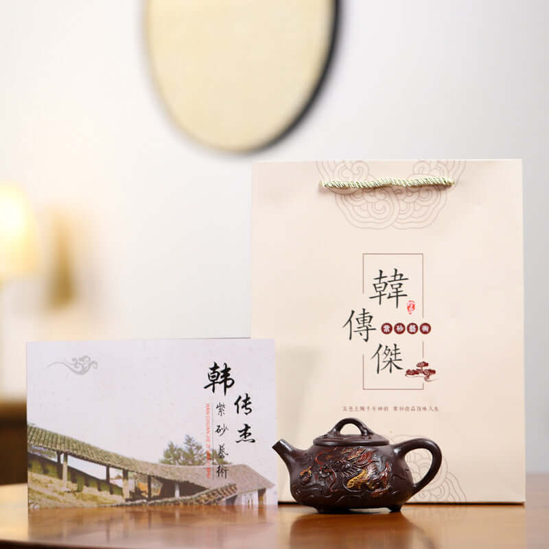 Handmade Yixing purple sand teapot displayed with a certificate and gift bag, highlighting traditional craftsmanship.