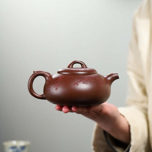 Handmade Yixing purple sand teapot held in hand, featuring elegant design and traditional craftsmanship.