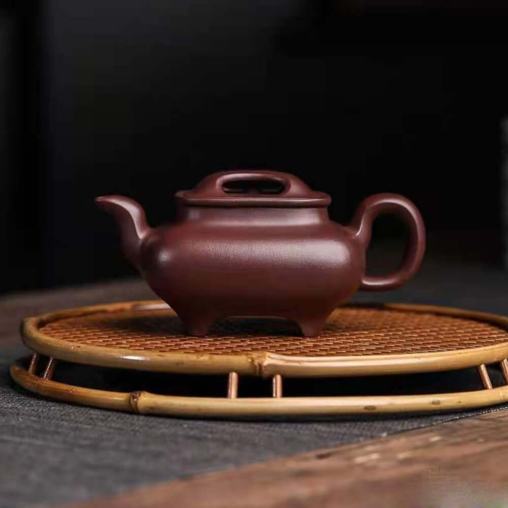 Handmade Yixing purple sand teapot on a bamboo tray, showcasing high-quality craftsmanship and traditional design.