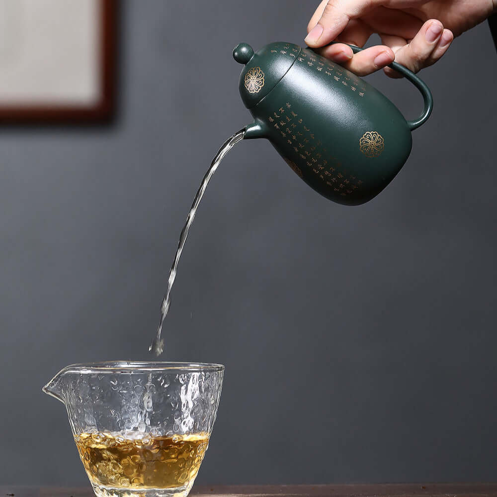 Handmade Yixing purple sand teapot pouring tea into a glass cup, showcasing traditional kung fu tea set artistry.
