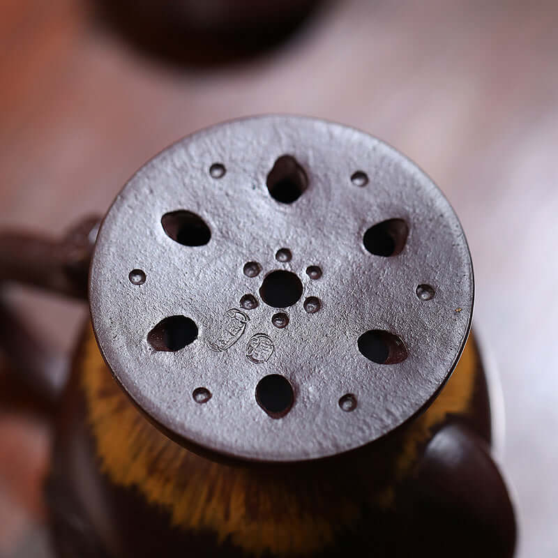Top view of a handmade Yixing purple sand teapot with traditional perforated spout design.