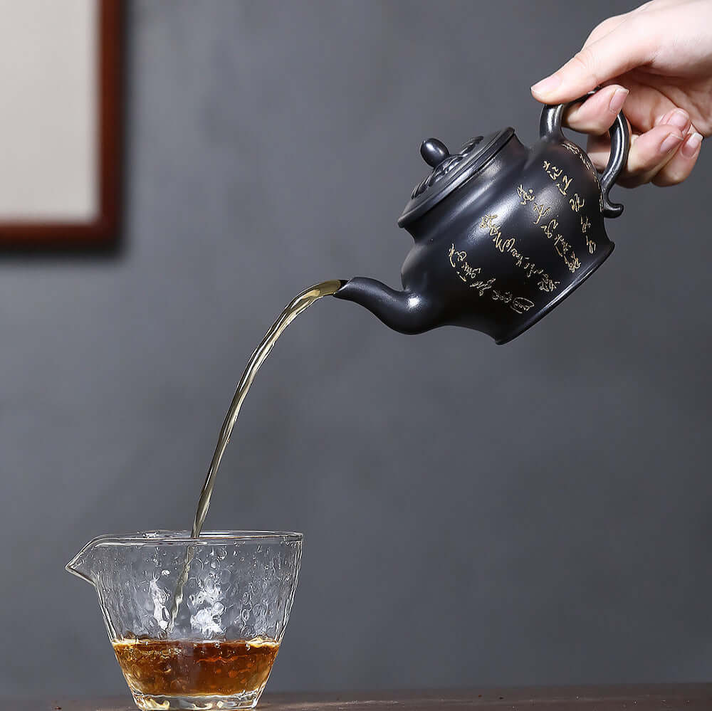 Handmade Yixing purple sand teapot pouring tea into glass cup, showcasing traditional Kung Fu tea craftsmanship.