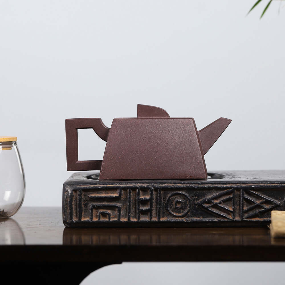 Handmade Yixing purple sand teapot sitting on a decorative wooden tray, showcasing unique square design.