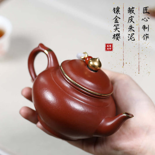 Handmade Yixing purple sand teapot with gold inlay, cherry blossom design, and original mineral surface, perfect for tea enthusiasts.
