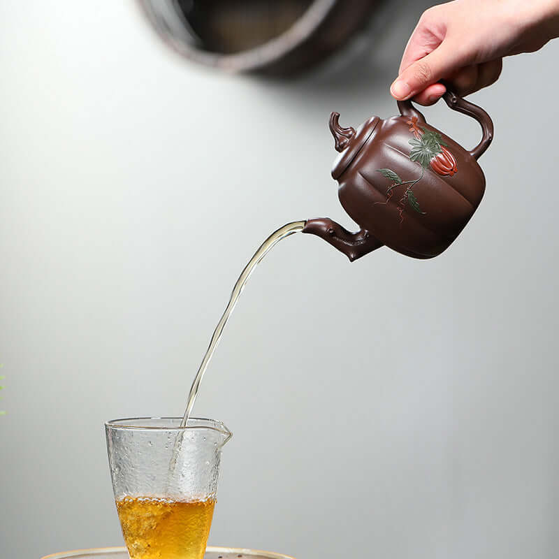 Handmade Yixing purple sand teapot pouring tea into a glass, showcasing traditional craftsmanship and elegance.