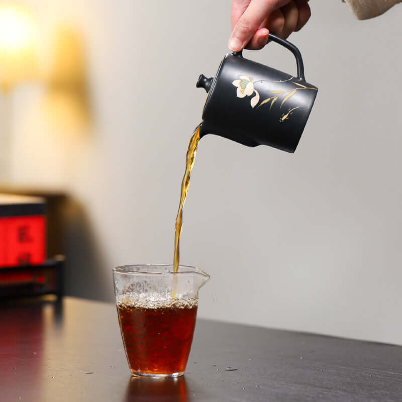 Handmade Yixing purple sand teapot pouring tea into a clear glass cup, showcasing traditional Kung Fu tea style.