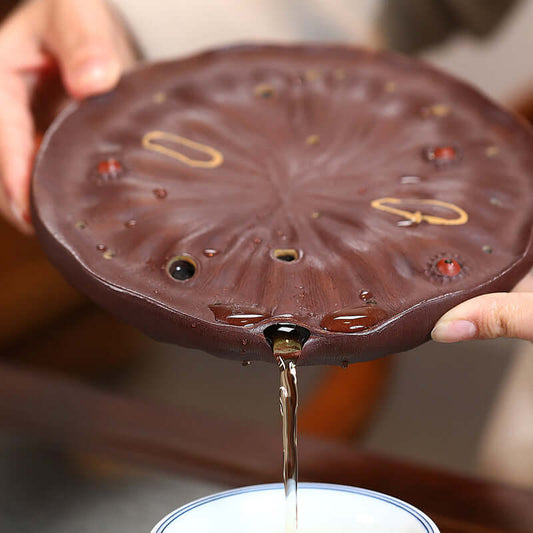 Handmade Yixing purple sand lotus pot pad with tea pouring, showcasing craftsmanship and unique design.