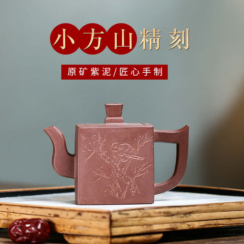 Handmade Yixing purple sand teapot, small square design with intricate engraving, showcasing traditional craftsmanship.