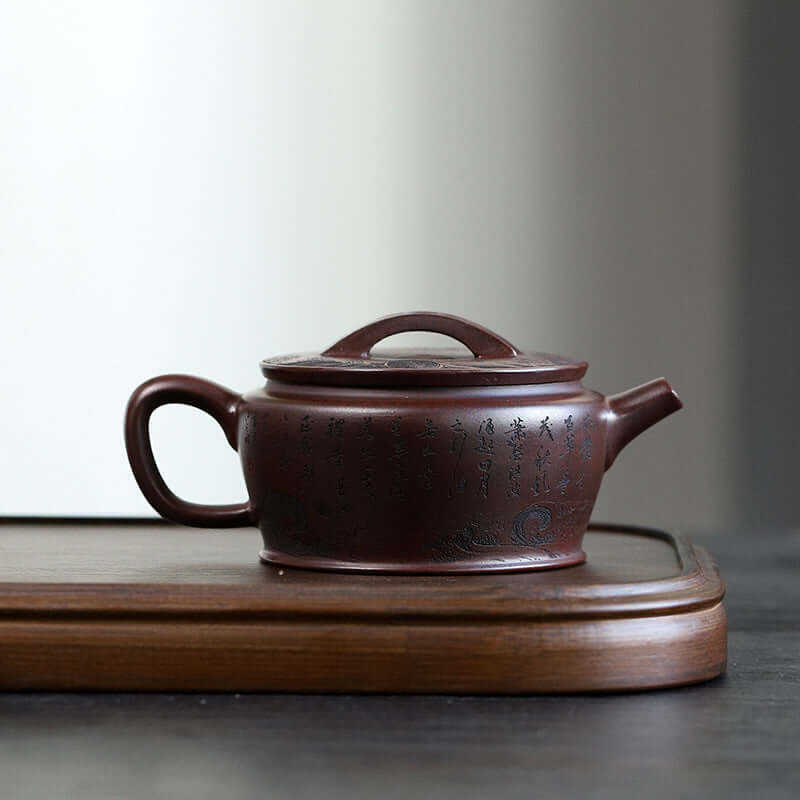 Handmade Yixing purple sand teapot with intricate inscriptions, showcasing traditional craftsmanship and elegant design.