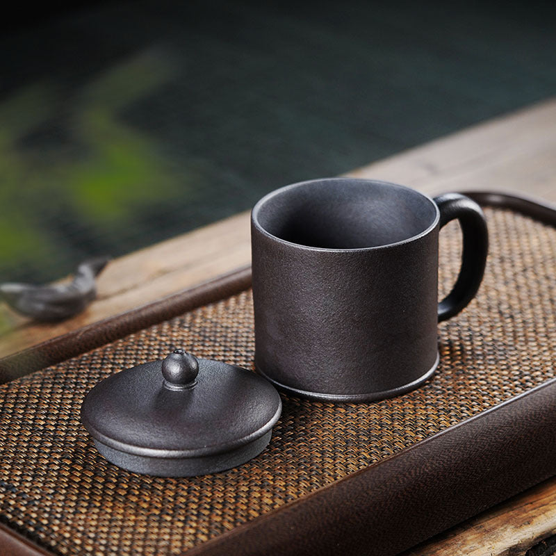 Handmade Yixing purple sand tea cup and lid on a bamboo mat, showcasing original craftsmanship and large capacity.