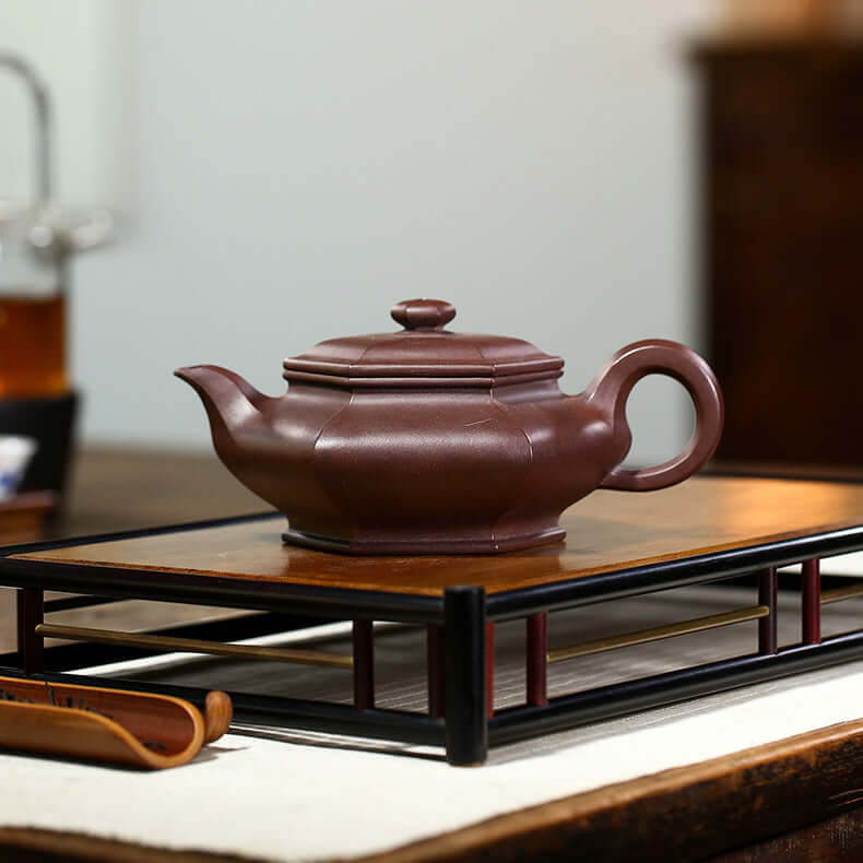 Handmade Yixing purple sand teapot on a wooden tray, showcasing craftsmanship and elegance for tea enthusiasts.