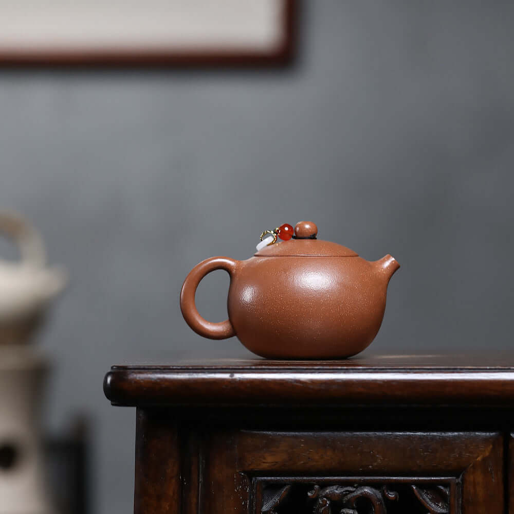 Handmade Yixing purple sand teapot on wooden table, showcasing original craftsmanship in a charming design.